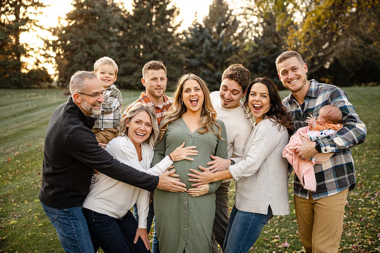 A multi-generational family standing in a field, grouped around a pregnant woman.